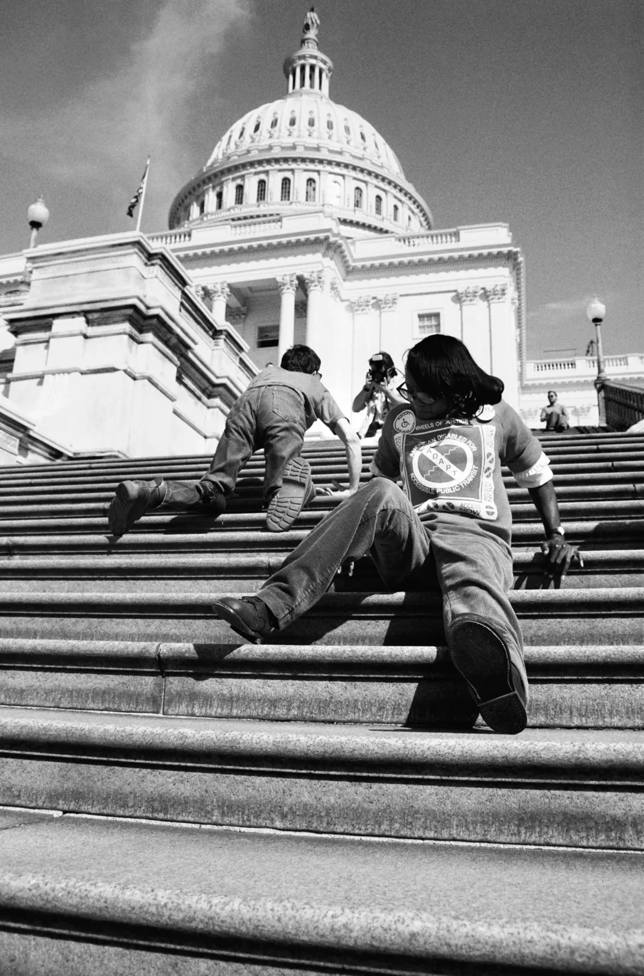 ADAPT activists leave their wheelchairs to ascend the steps to the US Capitol.